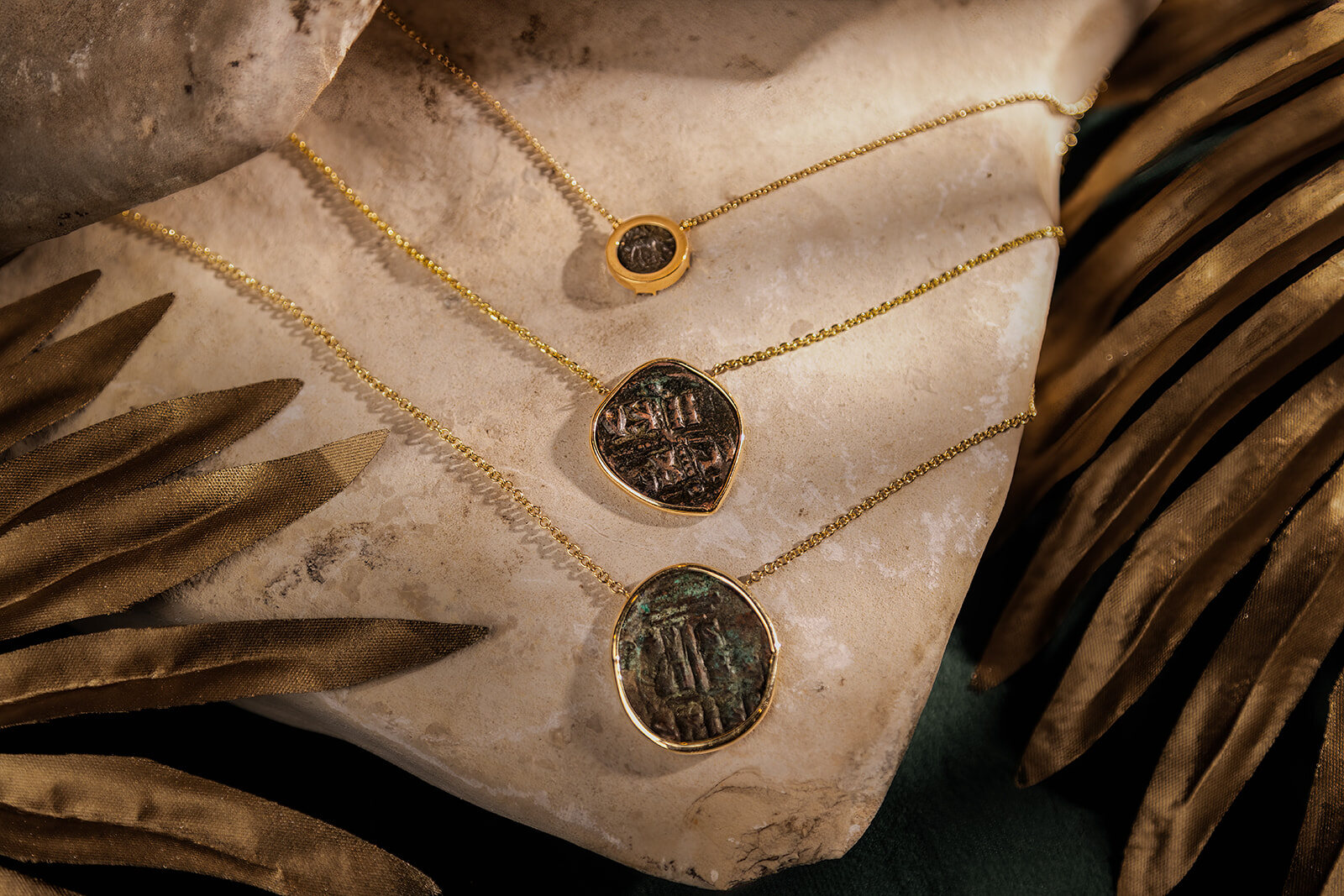 Handmade coin jewelry photographed on a natural textured surface