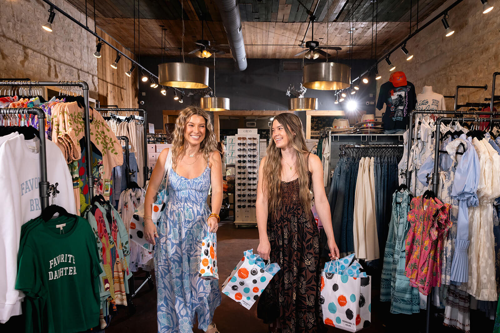 Two shoppers carrying bags through a brightly lit Hill Country boutique, photographed for the store's brand library